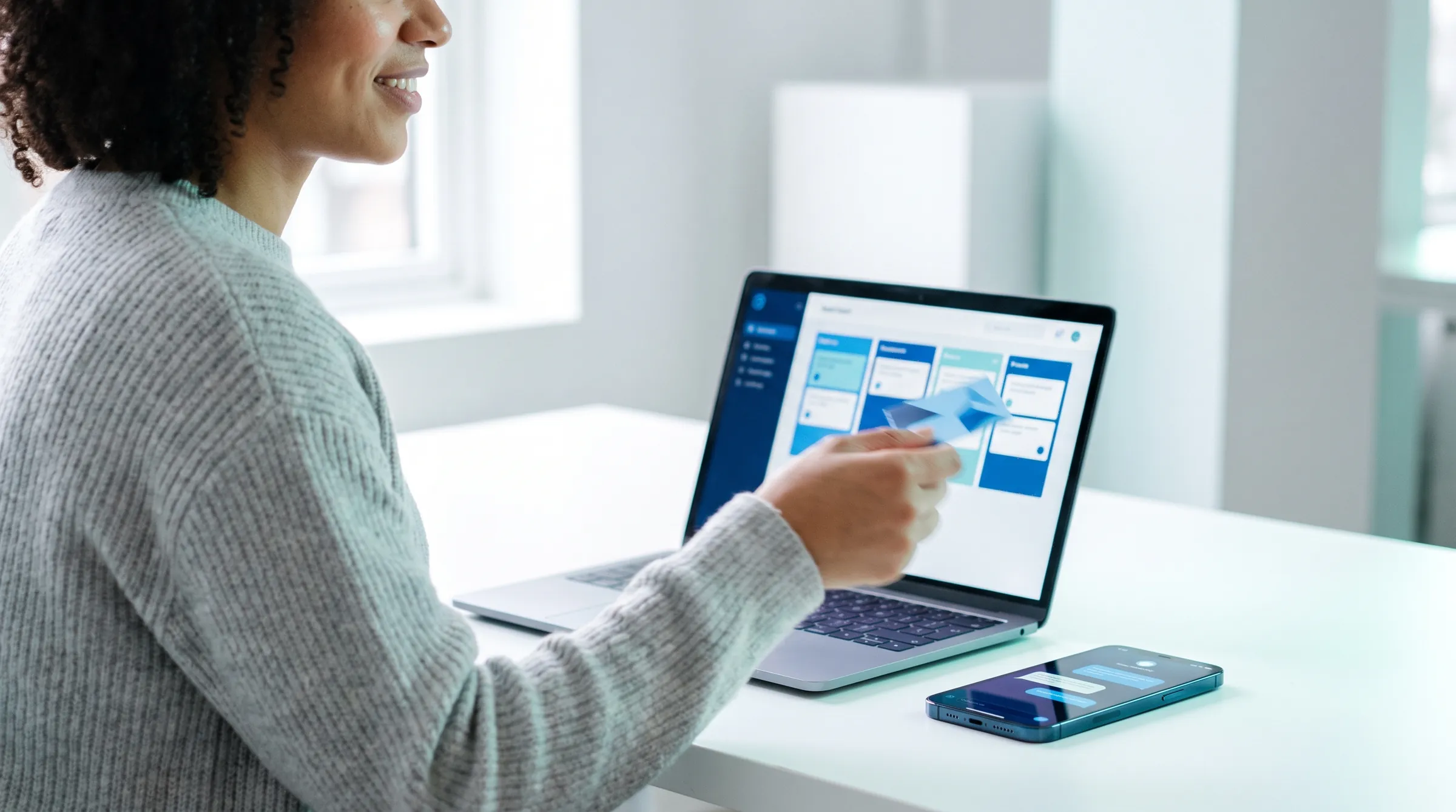 Atendente organizando cartões de um funil de vendas no notebook, com o celular ao lado
