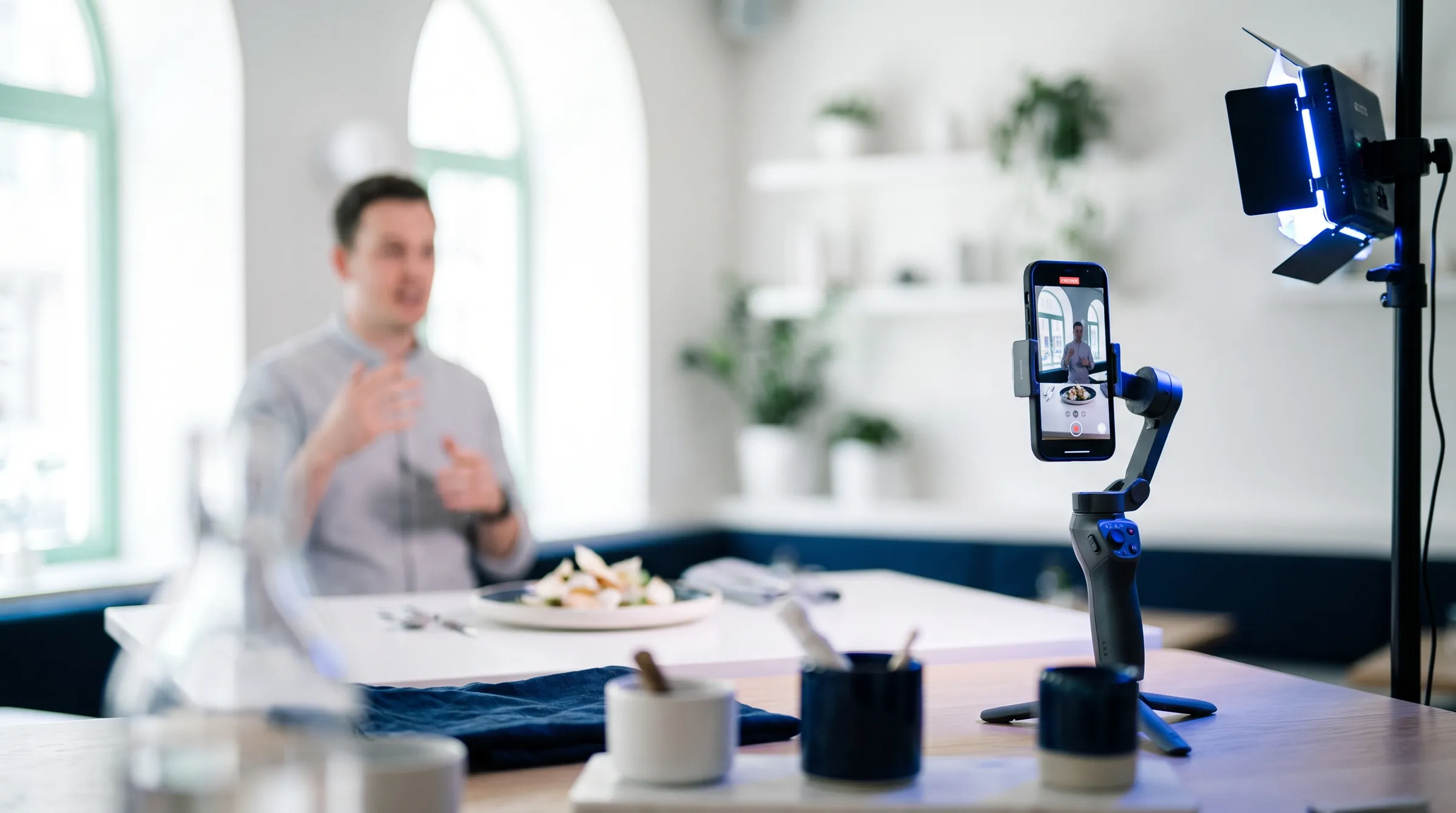 Celular em um estabilizador gravando um apresentador à mesa, com luz de estúdio