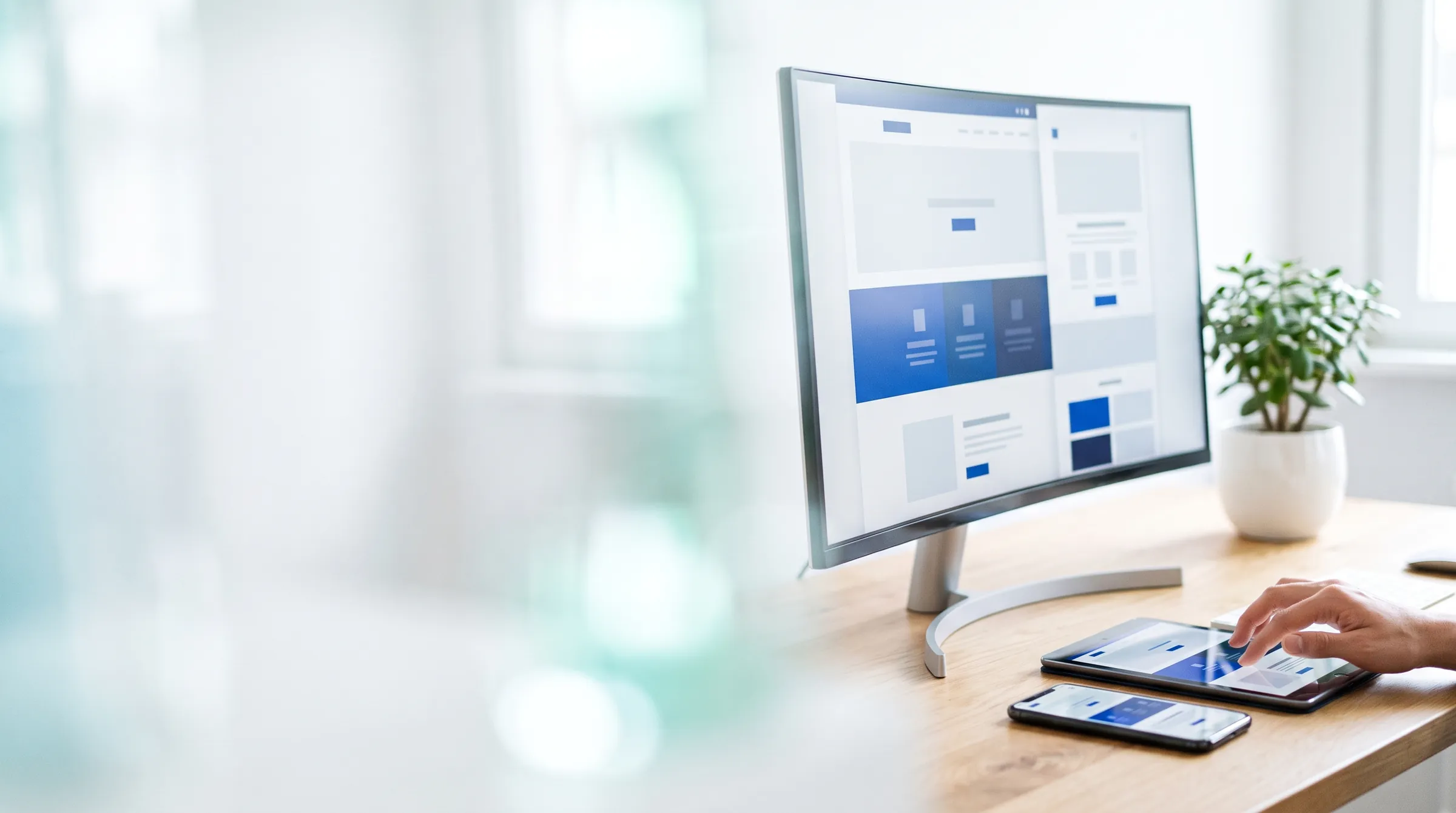 Monitor com o layout de um site e um tablet com a versão para celular sobre a mesa