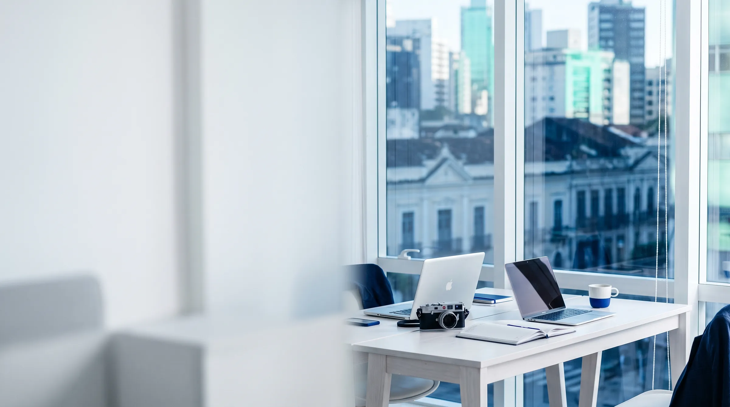 Escritório claro com mesas de trabalho e vista para a cidade