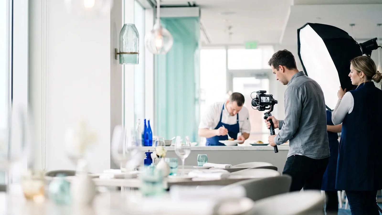 Equipe gravando um vídeo com câmera e luz dentro de um restaurante
